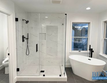 a remodeled kitchen with white stand alone tub and stand up shower, glass panel , black finishing
