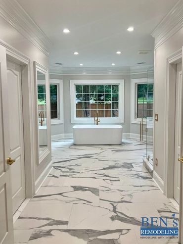 master bathroom by BEN's Remodeling with stand alone tub, white marble tiles, gold finishing