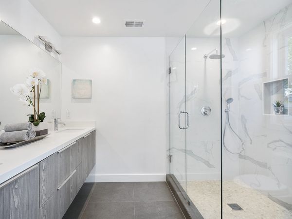 remodeled bathroom with stand up shower and a glass door with marble look tiles