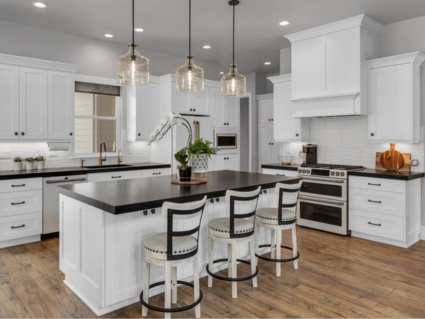 a remodeled kitchen, white cabinets, black quartz countertop island, 3 pendant lights, wooden floor