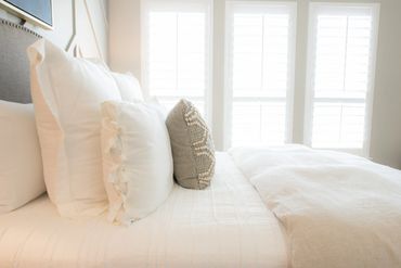 soft white bed with pillow in front of a window