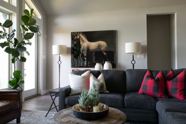 Living room with grey couch, red pillows, and photo of a horse on the wall