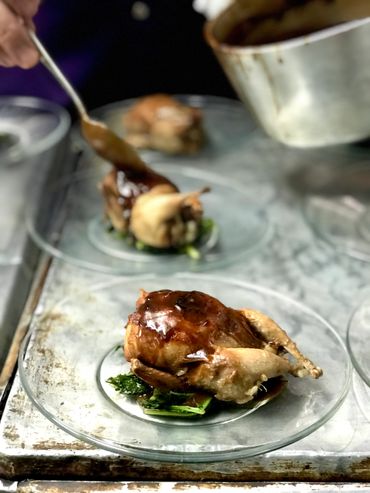 chef pouring sauce over plated quail 
