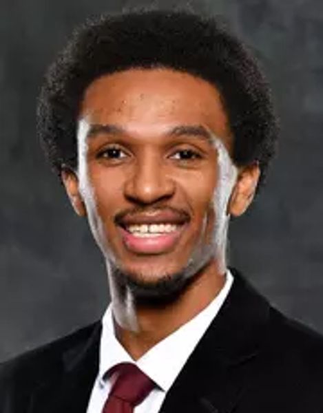 Professional portrait of a young man in a suit and tie, smiling confidently.