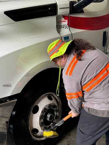 man degreasing semi truck tires
