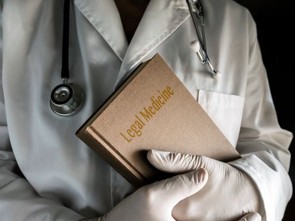 Doctor holds book of legal medicine, conceptual image