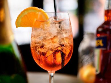 A refreshing cocktail garnished with an orange slice and filled with ice.