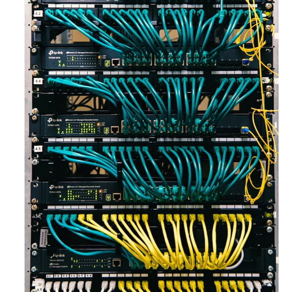 Network switches with organized blue and yellow Ethernet cables in a server rack.