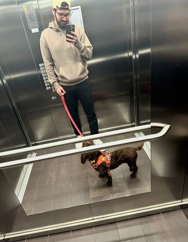 Man takes a selfie with his dog in an elevator mirror.
