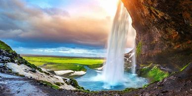 Waterfall cascading from a cliff into a river with a bright sky.