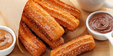Golden churros coated with sugar, served with chocolate and caramel dipping sauces.