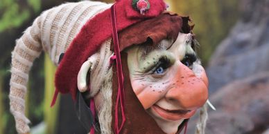 Close-up of a whimsical puppet with a large nose and colorful hat.