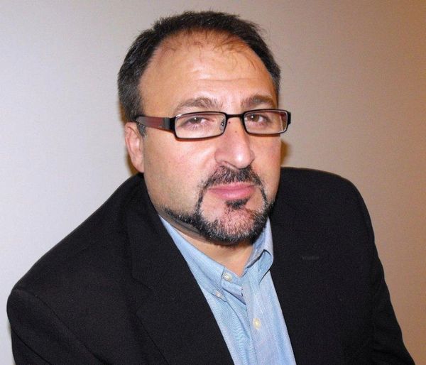 Man with beard and glasses in formal attire.