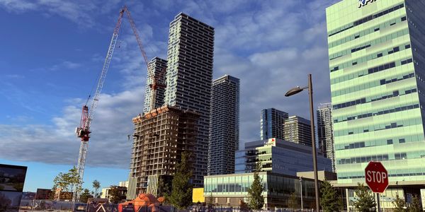 City skyline with construction and office buildings under a blue sky.