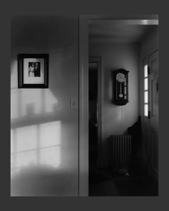 Front hall with a traditional pendulum clock. A small photograph of a couple hangs on a wall in the 