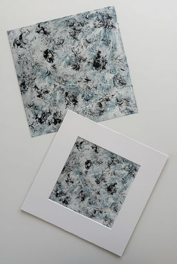 Two prints of the same artwork; an abstract acrylic of delicate black splashes on top cool icy blue.