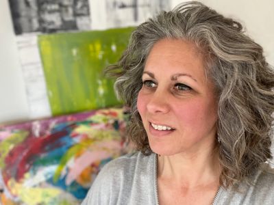Close up of the artist sitting near her paintings.