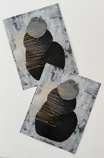 Two prints of the same artwork; three black and grey rocks stacked with gold horizontal lines.