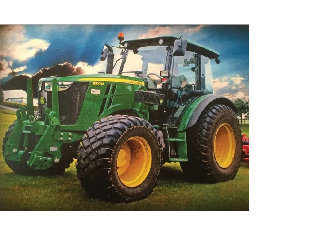 Green John Deere 5100M tractor on grass under a cloudy sky.