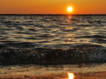 Sunset over a gently rippling ocean with the sun reflecting on the water.