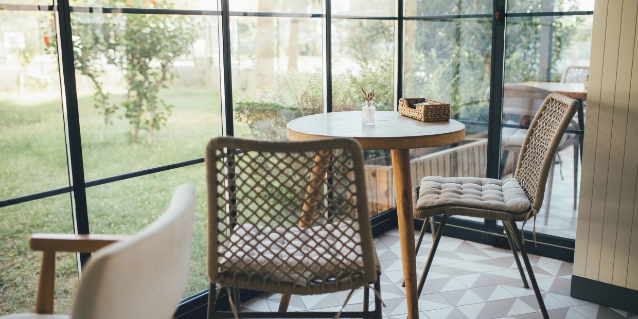 Sunny room with wicker chairs and round table.