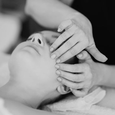 des mains qui font un massage sur un visage relaxe avec des produits de facials naturels