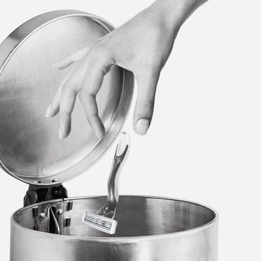 main qui jette un rasoir dans la poubelle