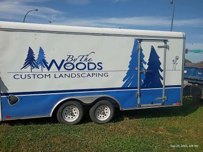 Trailer with custom landscaping logo featuring trees and text.