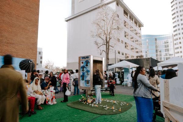 People gathered outdoors near a memorial display and tents.