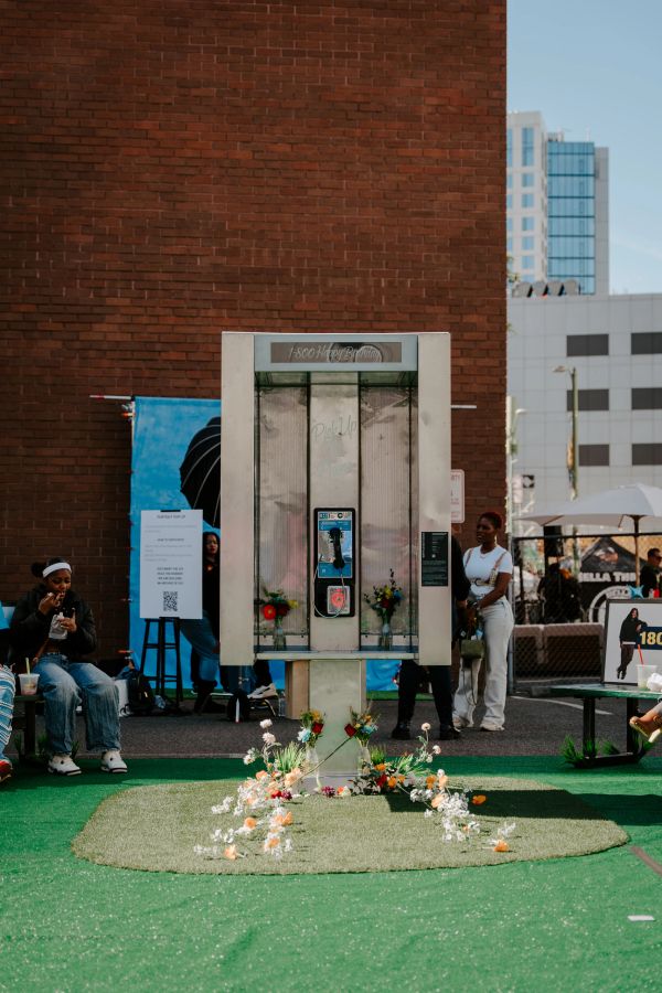 Old phone booth decorated with flowers outdoors.
