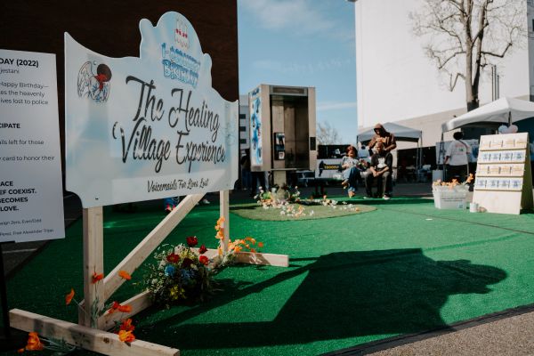 Celebration setup for "The Healing Village Experience" with people gathered.