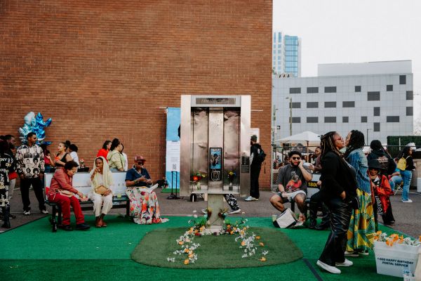 People gathered near a vintage phone booth with flowers and decorations.