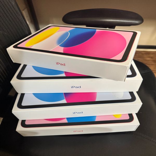 Stack of four new iPad boxes on a black chair.