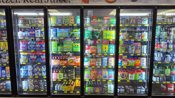 Refrigerator shelves stocked with assorted craft beers and beverages.
