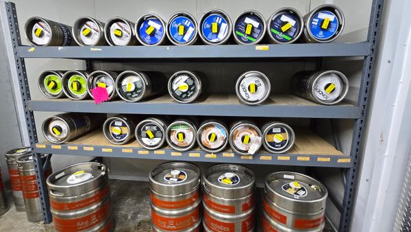 Metal kegs arranged on shelves in a storage room.