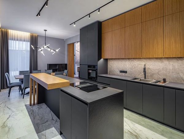 Two-toned kitchen with dark gray and wood cabinets, and a large island.