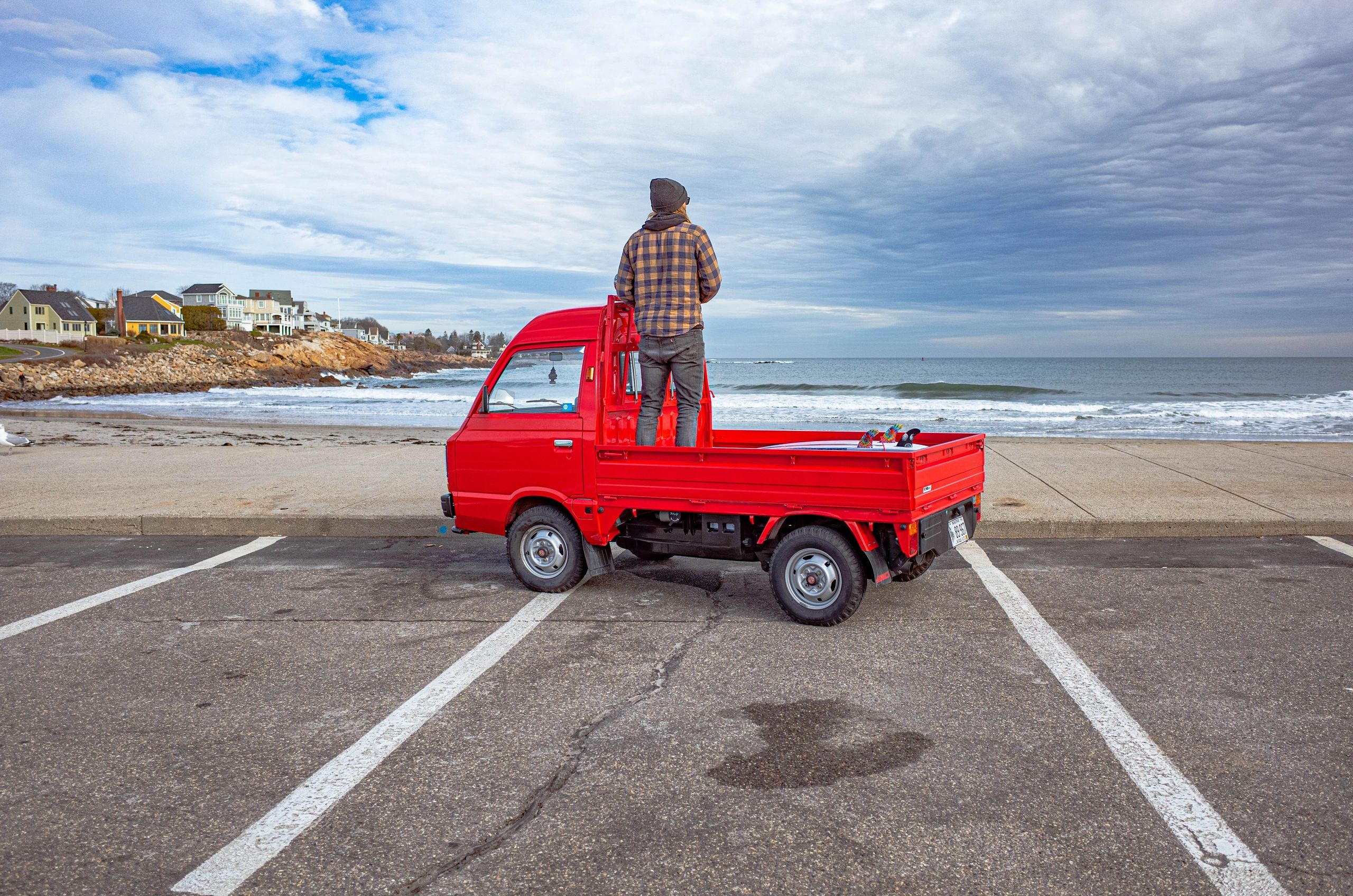 Red Subaru Sambar Kei truck on a Maine beach, headlining OIWA blog for mini truck enthusiasts.