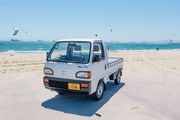 1990 Honda Acty kei truck on beach showcasing OIWA's quality mini trucks, ideal for versatile use.