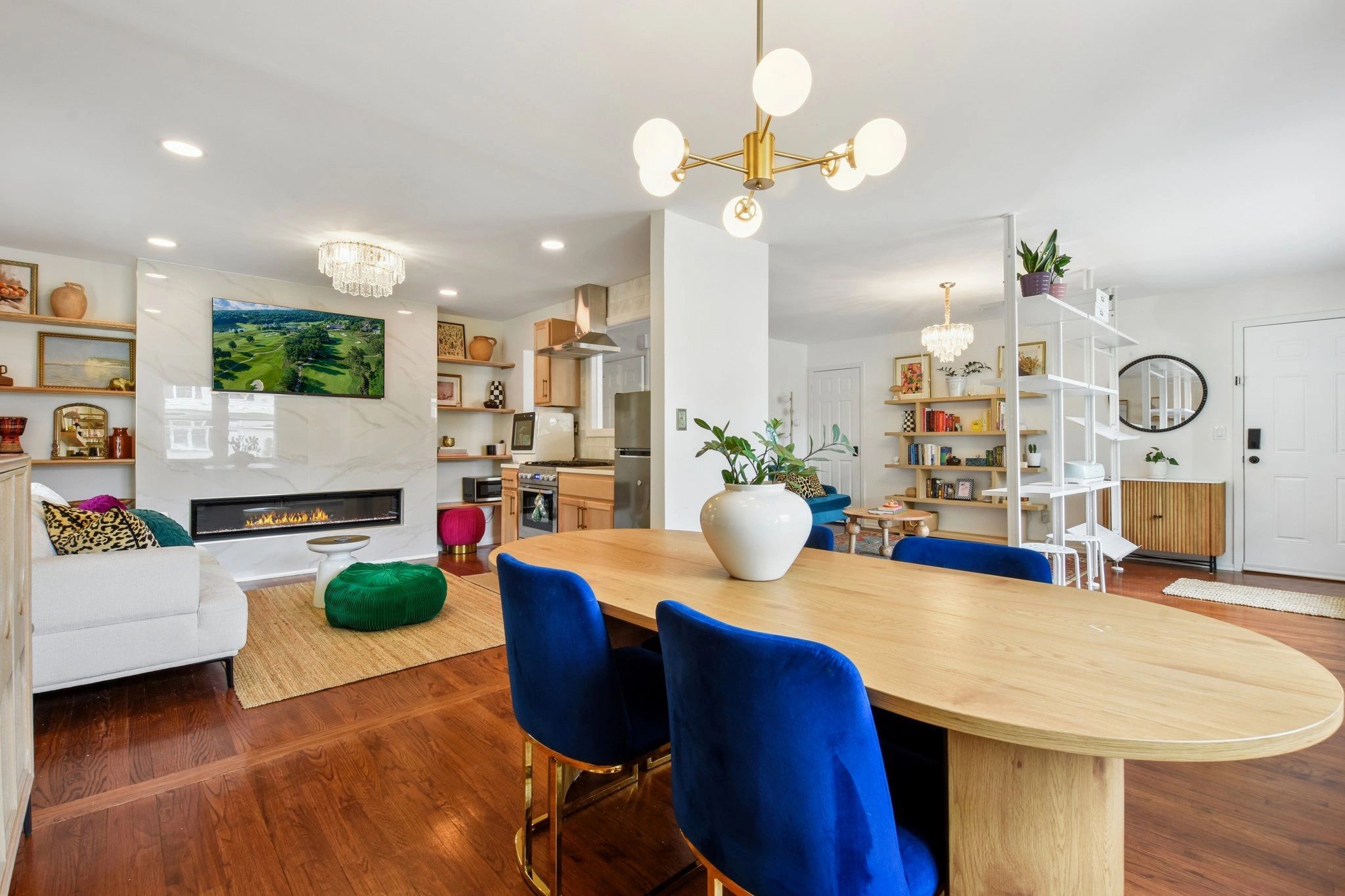 Open-concept living and dining area with modern fireplace and blue velvet chairs.