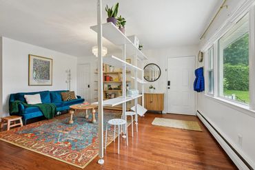Bright living room with blue sofa, colorful rug, and open shelving.