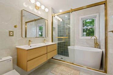 Modern bathroom with gold accents and a freestanding bathtub.