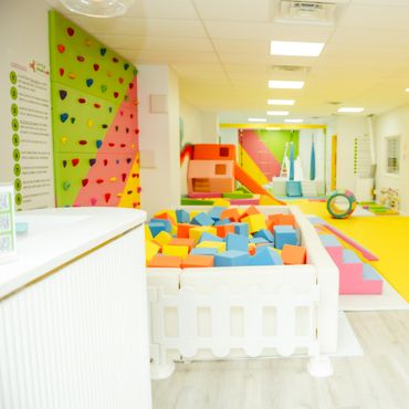 Bright and colorful indoor kids' play area with foam blocks and climbing wall.