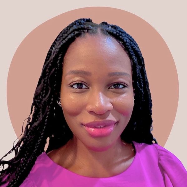 Portrait of a smiling woman with braided hair and a vibrant pink top.