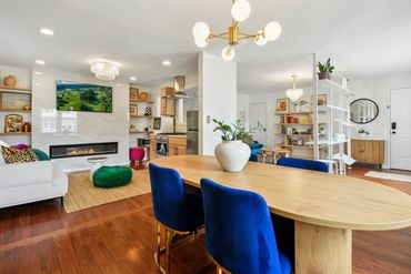 Open-concept living and dining area with modern fireplace and blue velvet chairs.