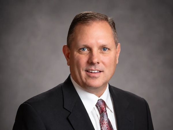 Professional headshot of a man in a suit and tie.