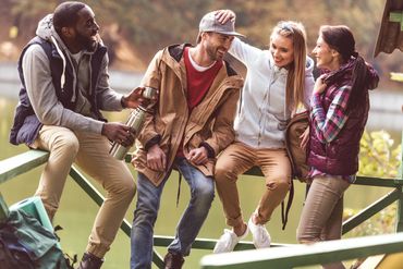 Male and female friends are gathered at the park to talk.