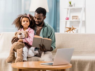 Dad reading to little girl with stuffed animal