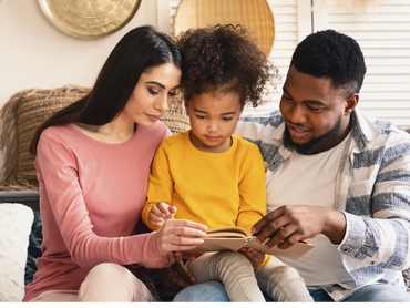 Couple is helping the daughter read her book.