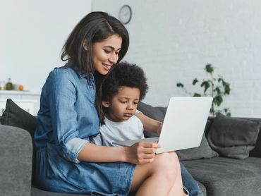 A mother reads something from the computer while her son is looking intently on.