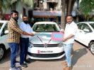 Three men standing by a white car exchanging keys.